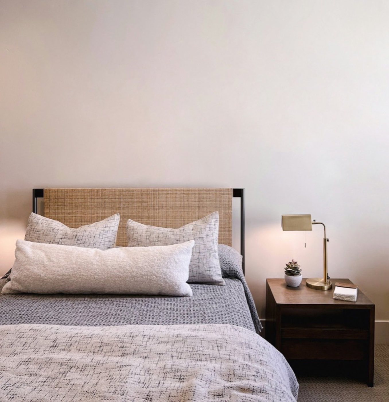 Calm motel bedroom with a cane headboard and a warm bedside lamp