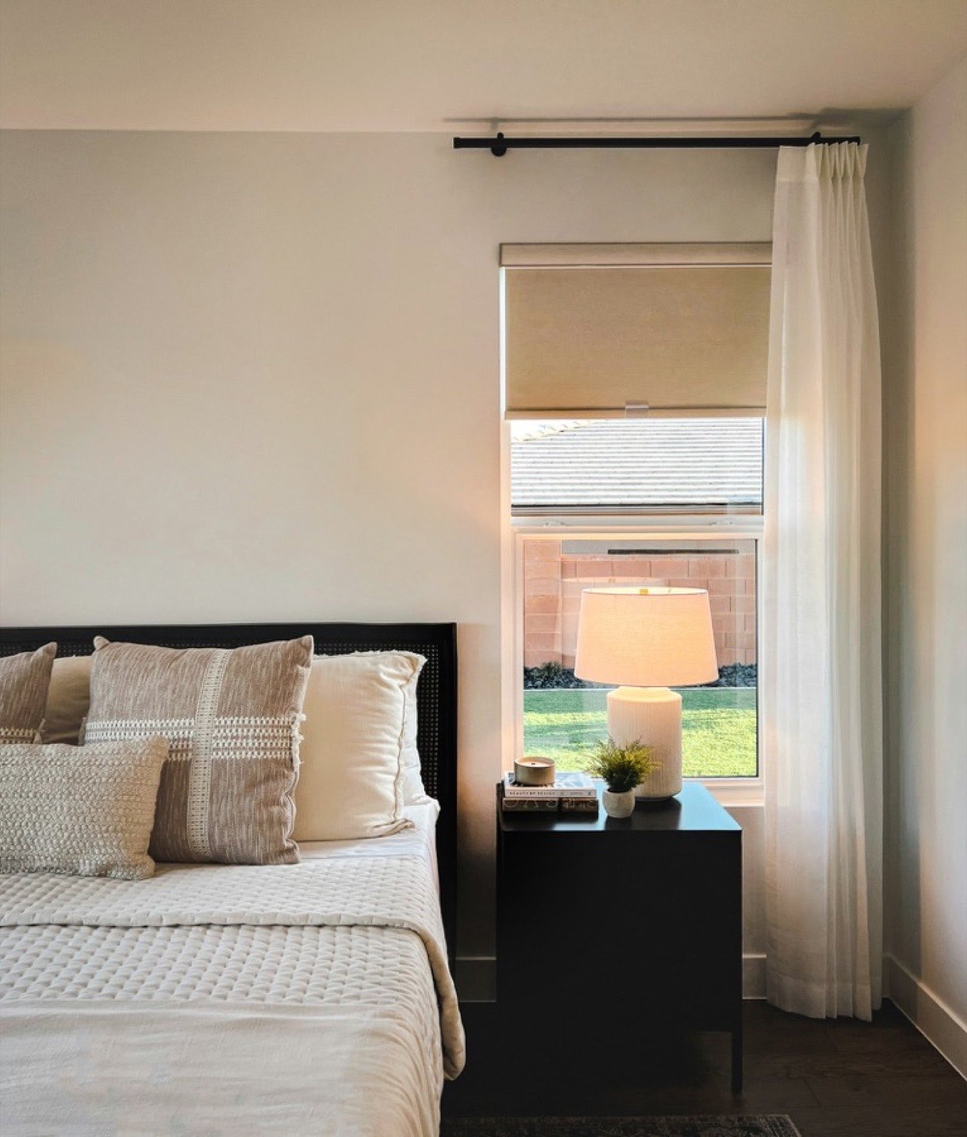 Warm, calm motel bedroom with a lamp lit beside a bright window
