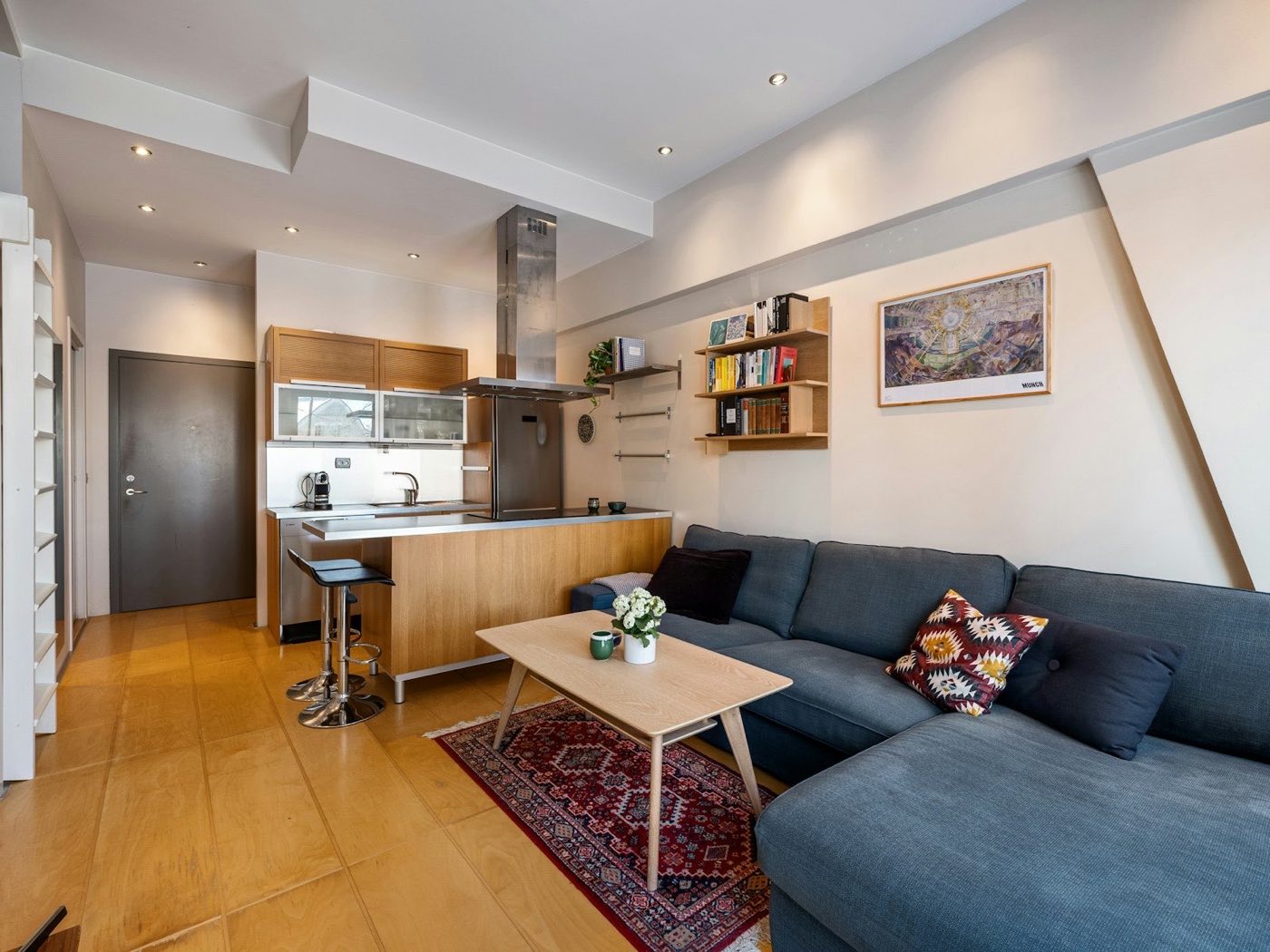 Small suite living area with a sofa and a compact kitchen behind it